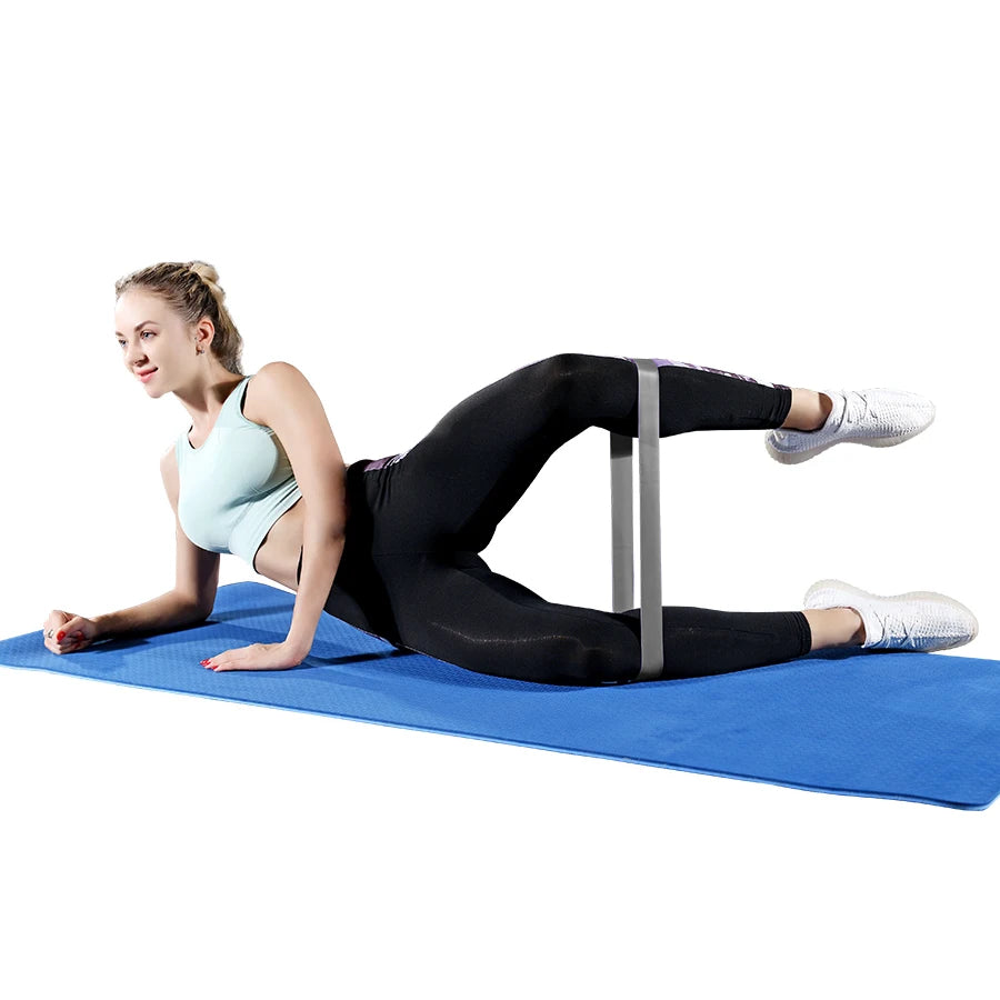 Mulher usando faixa fitness para treinos em casa enquanto faz exercício lateral no tapete azul
